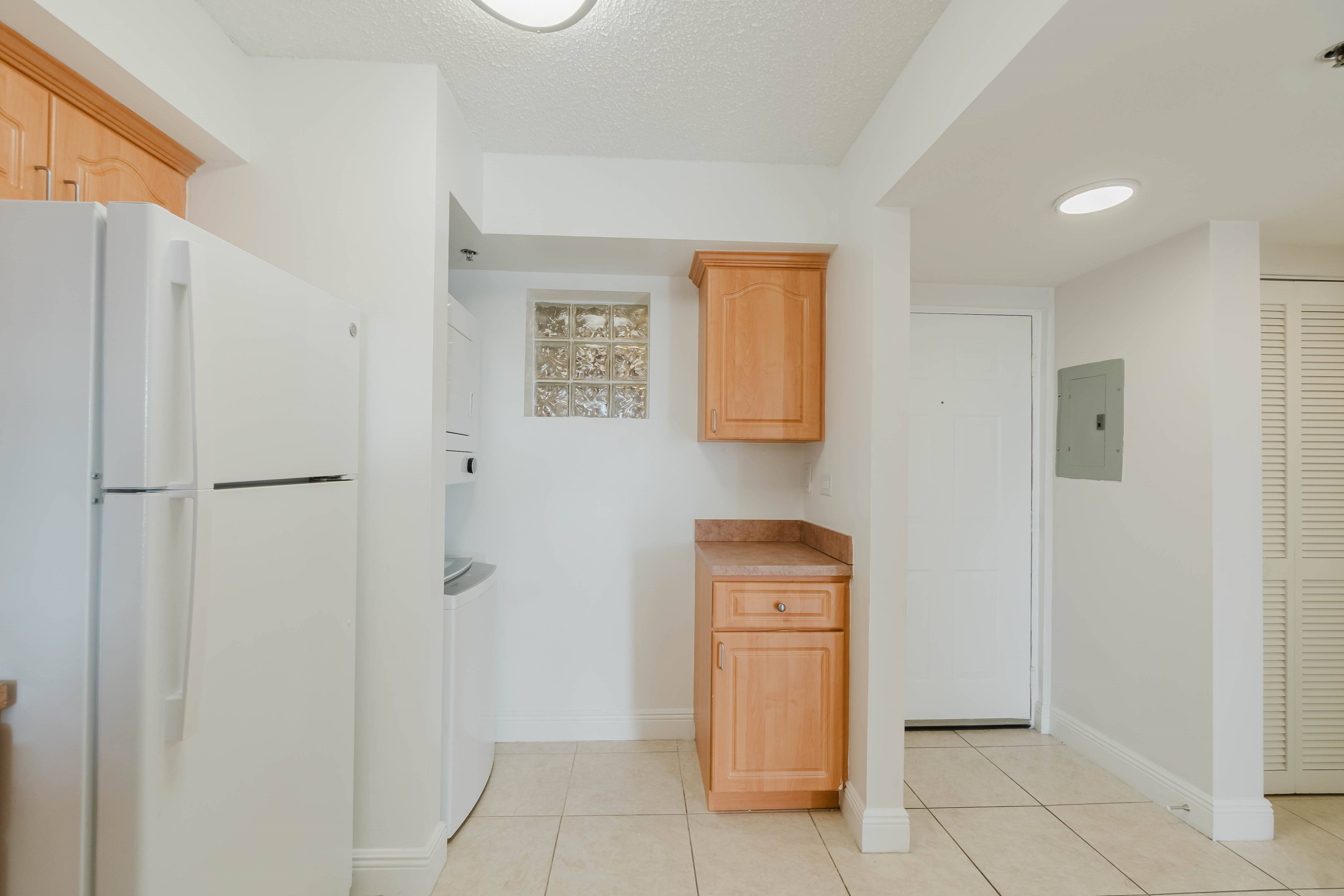 A kitchen with a white refrigerator and wooden cabinets.